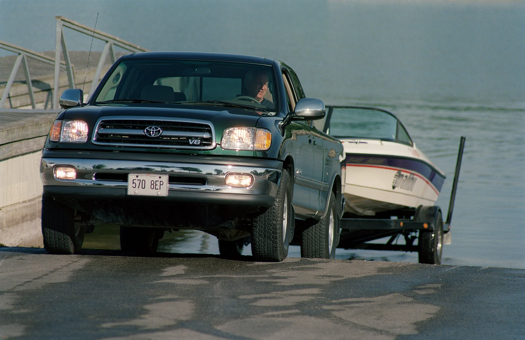 2000 Toyota Tundra towing a boat on a trailer up a launch ramp.